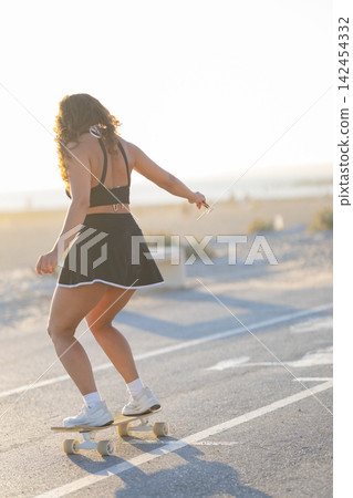 Skateboarding on the beach during sunset in a city with warm weather and a clear sky 142454332