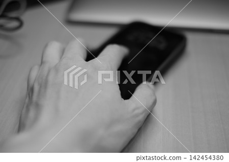 一隻手觸摸智慧型手機;一張黑白生活照。 一隻手觸摸智慧型手機;一張黑白生活照。 142454380