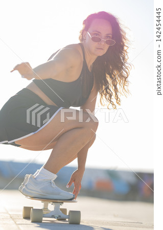 Skater practicing tricks on a board during sunny day at a skate park near the beach Skater practicing tricks on a board during sunny day at a skate park near the beach 142454445