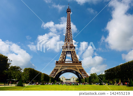 eiffel tower standing tall in serene paris with green grass and trees from ground level front view in france architecture travel destination natural setting clean background. eiffel tower standing tall in serene paris with green grass and trees from ground level front view in france architecture travel destination natural setting clean background. 142455219