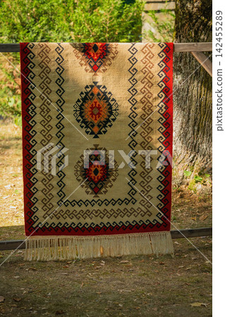 Traditional Kotel carpet with geometric ethnic ornament and decorative fringe displayed outdoors in Bulgaria. Authentic Bulgarian textile craftsmanship and folk heritage 142455289