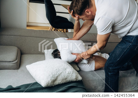 Man Silencing Woman With Pillow During Violent Domestic Dispute On Couch At Home Man Silencing Woman With Pillow During Violent Domestic Dispute On Couch At Home 142455364