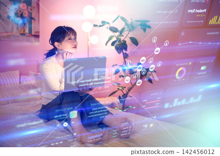 A young woman using a laptop in bed A young woman using a laptop in bed 142456012