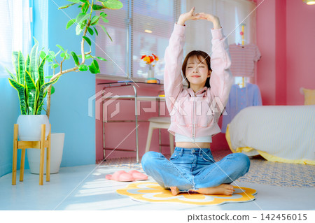 A woman stretches on a yoga mat. A woman stretches on a yoga mat. 142456015