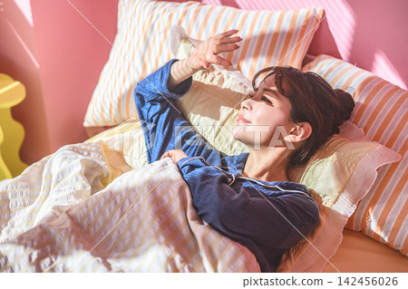 A woman lying in bed with her hand outstretched. 142456026