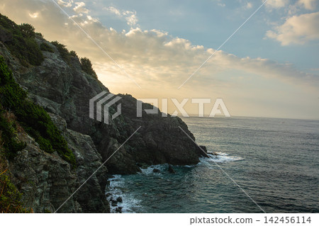 The rugged rock face and seascape illuminated by the setting sun The rugged rock face and seascape illuminated by the setting sun 142456114