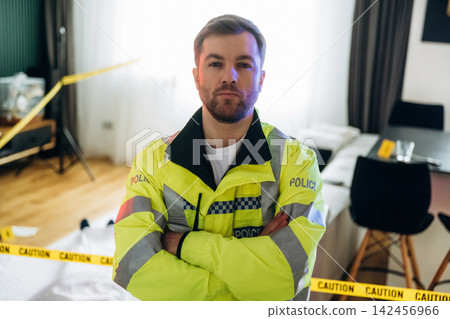 Police detective in reflective yellow jacket stands confidently at a murder scene, with caution tape and evidence markers visible in a well-lit indoor setting Police detective in reflective yellow jacket stands confidently at a murder scene, with caution tape and evidence markers visible in a well-lit indoor setting 142456966