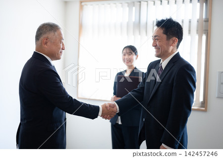 Business people exchanging smiles and handshakes after a successful business deal. Business people exchanging smiles and handshakes after a successful business deal. 142457246