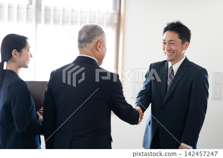 Business people exchanging smiles and handshakes after a successful business deal. Business people exchanging smiles and handshakes after a successful business deal. 142457247
