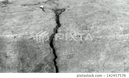 A monochromatic image showing deep cracks in a concrete surface. 142457576