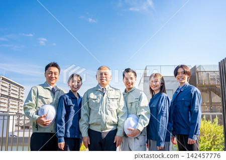 在藍天下，建築公司和承包商的工人們面帶笑容地排成一列。 142457776