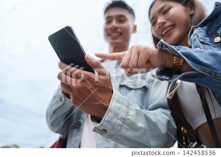 Asian couple using smartphone together outdoors for digital travel navigation 142458536