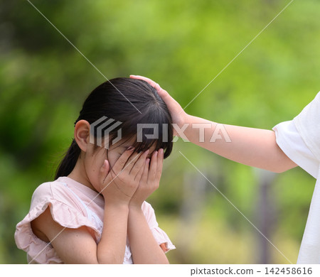 The older sister is stroking the head of her crying younger sister. The older sister is stroking the head of her crying younger sister. 142458616
