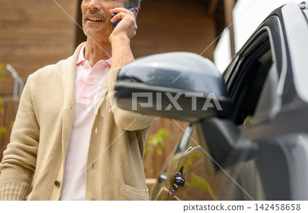 一位老人在車旁用智慧型手機通話。 一位老人在車旁用智慧型手機通話。 142458658