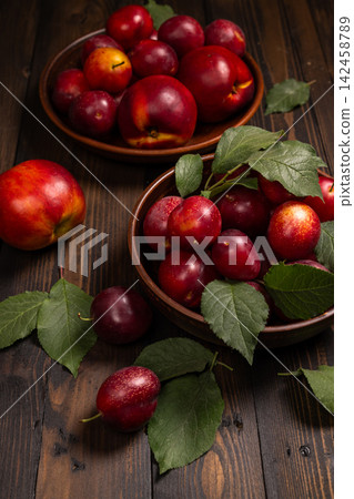 Ripe plums and nectarines in bowls on rustic wooden table Ripe plums and nectarines in bowls on rustic wooden table 142458789