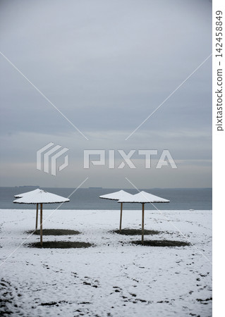 Beach straw umbrellas covered in snow  142458849