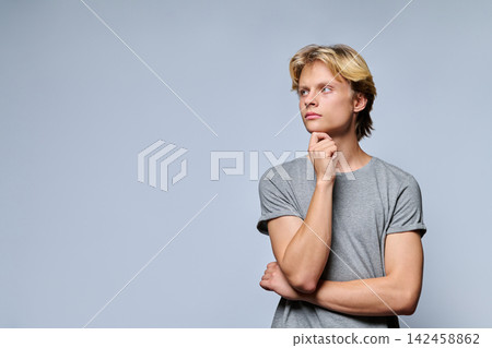 Portrait of thoughtful teenage boy looking away with hand on chin 142458862