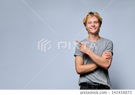 Portrait of smiling teenage boy pointing thumb at copy space 142458873