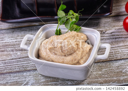 Creamy forshmak in white ceramic dish with fresh herb garnish on rustic wood table Creamy forshmak in white ceramic dish with fresh herb garnish on rustic wood table 142458892