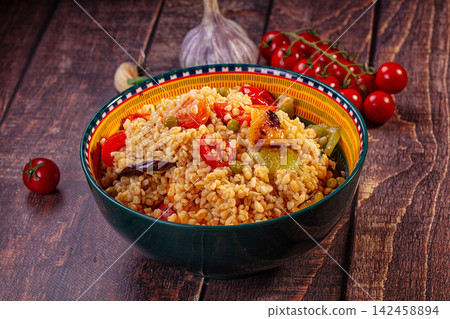 Bulgur salad with roasted vegetables in colorful bowl on rustic wood Bulgur salad with roasted vegetables in colorful bowl on rustic wood 142458894