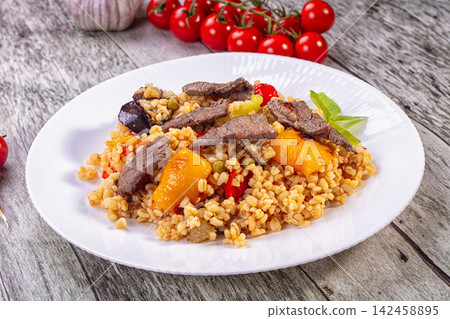 Bulgur pilaf with beef and roasted vegetables on white plate Bulgur pilaf with beef and roasted vegetables on white plate 142458895