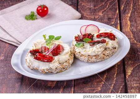 Healthy rice cakes with cream cheese, sun-dried tomatoes and radish on white plate Healthy rice cakes with cream cheese, sun-dried tomatoes and radish on white plate 142458897