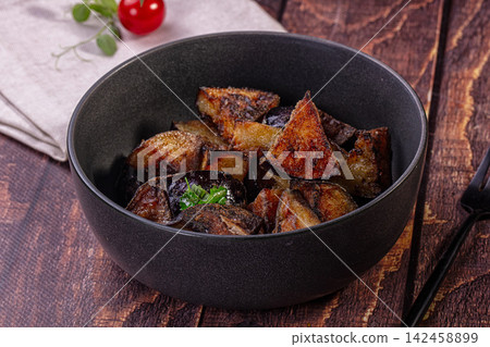 Crispy fried eggplant wedges with fresh herbs in dark bowl on wooden table Crispy fried eggplant wedges with fresh herbs in dark bowl on wooden table 142458899