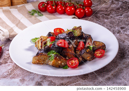 Fried eggplant salad with cherry tomatoes cilantro and peanuts on white plate Fried eggplant salad with cherry tomatoes cilantro and peanuts on white plate 142458900
