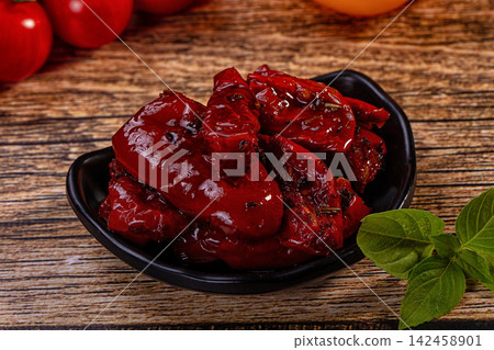 Sun dried tomatoes in black bowl with basil on rustic wood Sun dried tomatoes in black bowl with basil on rustic wood 142458901