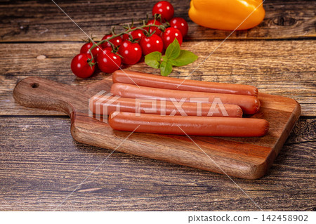 Raw sausages on wooden cutting board with cherry tomatoes and basil Raw sausages on wooden cutting board with cherry tomatoes and basil 142458902