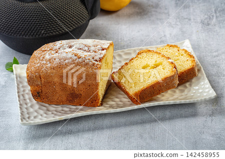 Sliced pound cake dusted with powdered sugar on textured white plate Sliced pound cake dusted with powdered sugar on textured white plate 142458955