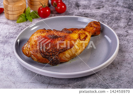 Roasted chicken leg on gray plate with cherry tomatoes and basil 142458970