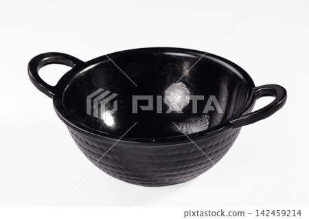 Black ceramic bowl with textured exterior and two handles on white background Black ceramic bowl with textured exterior and two handles on white background 142459214