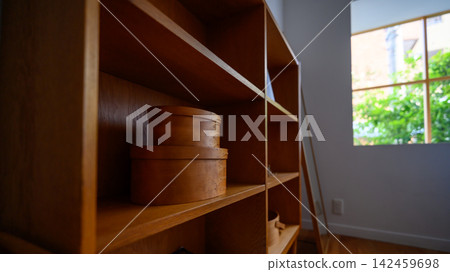 Wooden shelves in a room where natural light streams in. Wooden shelves in a room where natural light streams in. 142459698