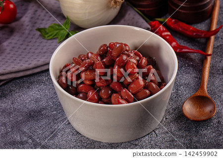 Cooked red kidney beans in white bowl with chili peppers and onion Cooked red kidney beans in white bowl with chili peppers and onion 142459902