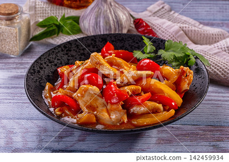 Chicken stir fry with red and yellow bell peppers in black bowl Chicken stir fry with red and yellow bell peppers in black bowl 142459934