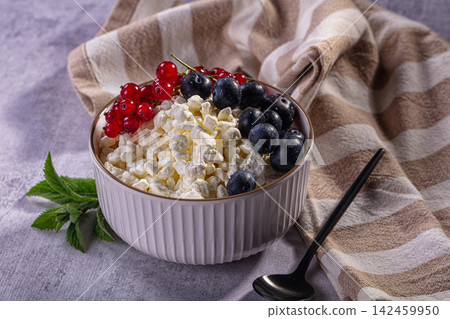 Cottage cheese bowl with blueberries and red currants on striped cloth Cottage cheese bowl with blueberries and red currants on striped cloth 142459950