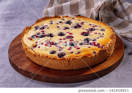 Blueberry and red currant pie on wooden board with striped cloth background Blueberry and red currant pie on wooden board with striped cloth background 142459951