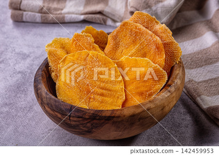 Dried mango slices in wooden bowl with rustic cloth background Dried mango slices in wooden bowl with rustic cloth background 142459953
