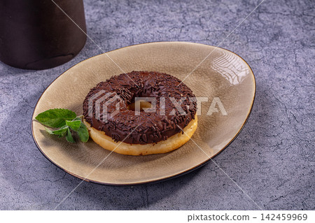 Chocolate frosted donut with sprinkles on ceramic plate with mint garnish Chocolate frosted donut with sprinkles on ceramic plate with mint garnish 142459969