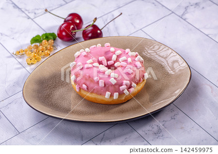 Pink frosted donut with marshmallow sprinkles on ceramic plate beside fresh cherries and white currants Pink frosted donut with marshmallow sprinkles on ceramic plate beside fresh cherries and white currants 142459975