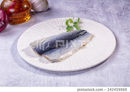 Raw herring fillets on textured white plate with fresh herbs and cooking ingredients Raw herring fillets on textured white plate with fresh herbs and cooking ingredients 142459988