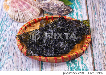 Nori seaweed sheets on woven bamboo tray with seashells on weathered wood 142459992