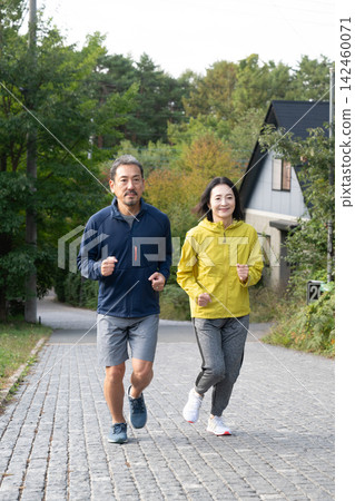 A middle-aged couple jogging along a trail in the Yatsugatake Mountains. Running, jogging. A middle-aged couple jogging along a trail in the Yatsugatake Mountains. Running, jogging. 142460071