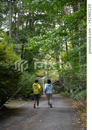 沿著山間小徑跑步和慢跑的女性的背影。 沿著山間小徑跑步和慢跑的女性的背影。 142460129