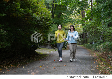 兩名女子並肩奔跑在高原上。 兩名女子並肩奔跑在高原上。 142460130