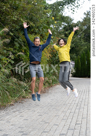A couple enjoying a free-spirited jump, run, and jog. A couple enjoying a free-spirited jump, run, and jog. 142460153