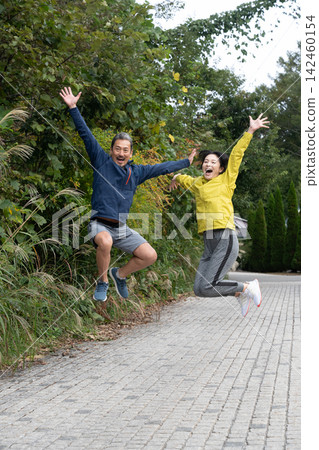 A middle-aged couple jumps for joy in a sense of accomplishment after running and jogging. 142460154