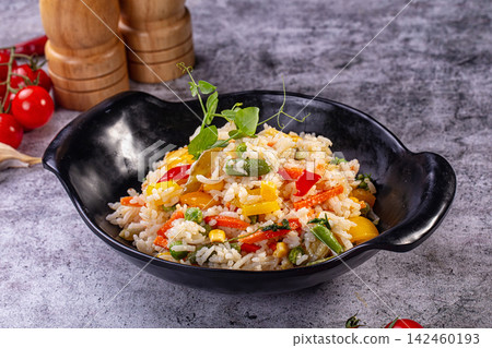 Colorful vegetable rice in black bowl with fresh garnish Colorful vegetable rice in black bowl with fresh garnish 142460193