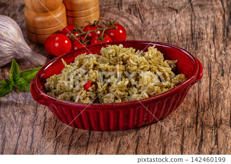 Pesto basmati rice in red bowl with fresh tomatoes, garlic, and basil on rustic wood background Pesto basmati rice in red bowl with fresh tomatoes, garlic, and basil on rustic wood background 142460199